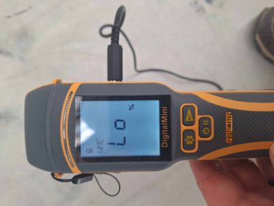 Technician using a Protimeter to measure concrete moisture before resin flooring installation