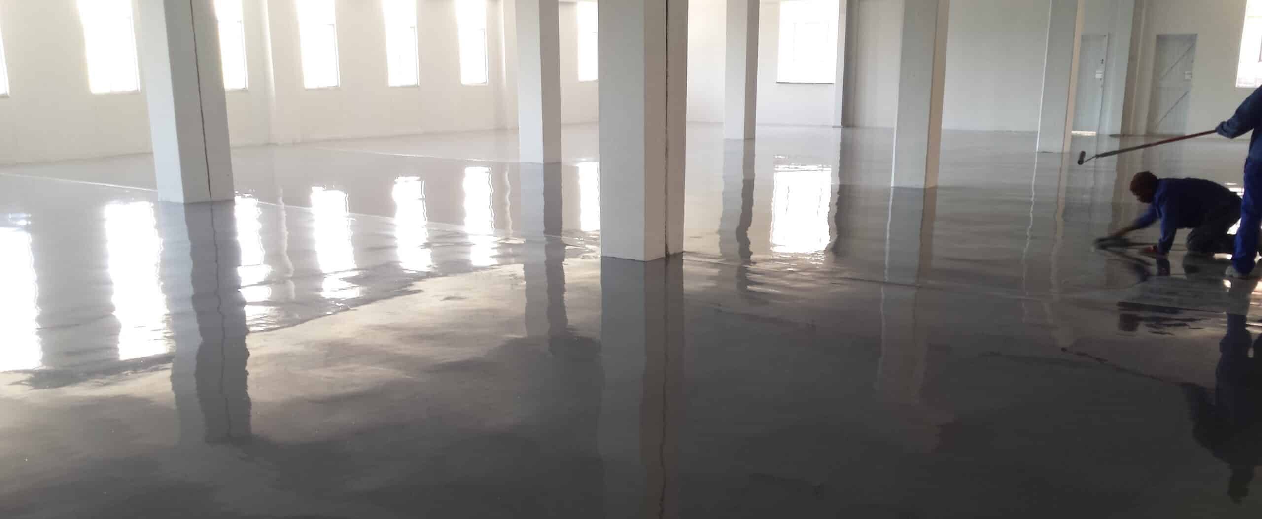 Applicators installing an epoxy flooring system onto a prepared concrete substrate